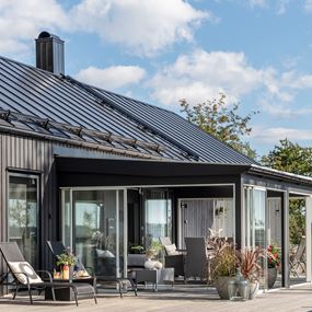 Svart plåttak på ett modernt svart hus och uterum